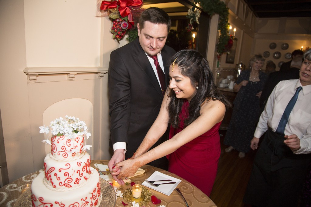 Bride and groom cutting cake at Indian wedding