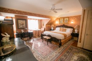 Guest room with pink fabric walls and rugs and dark wood furniture.