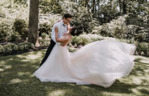 Ballerina in the gardens dancing with the groom. Her dress is a light pink color.