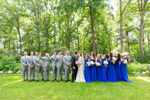 Men and women standing on grass in suits and dresses for a wedding.