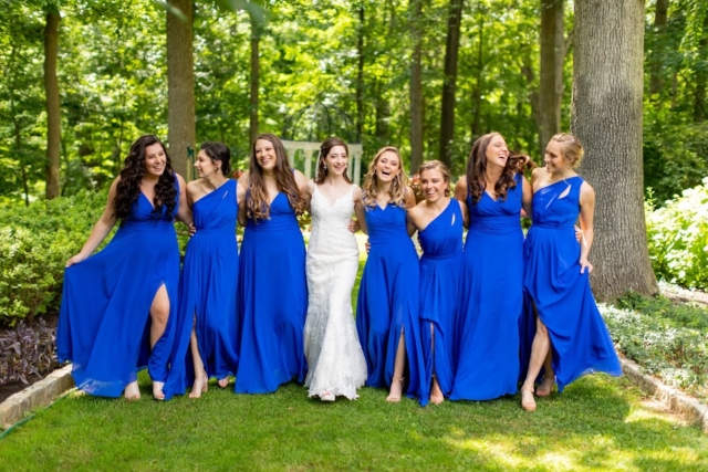 Royal blue bridesmaids dresses in green gardens with the bride in a white gown.