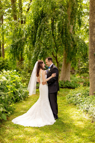 Bride and groom in the gardens with green grass around them.
